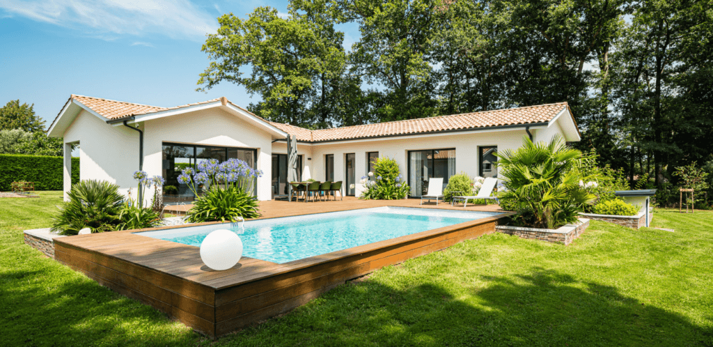 Une maison en L vue du jardin avec terrasse bois et piscine